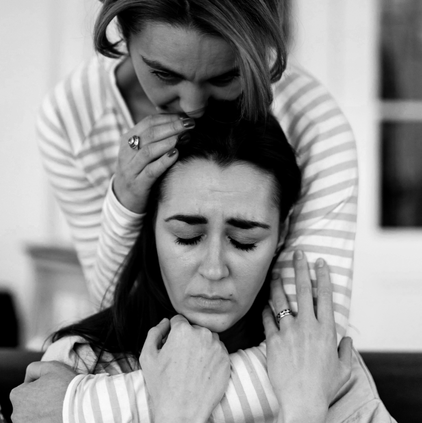 A couple comforting each other on steps outside their home.