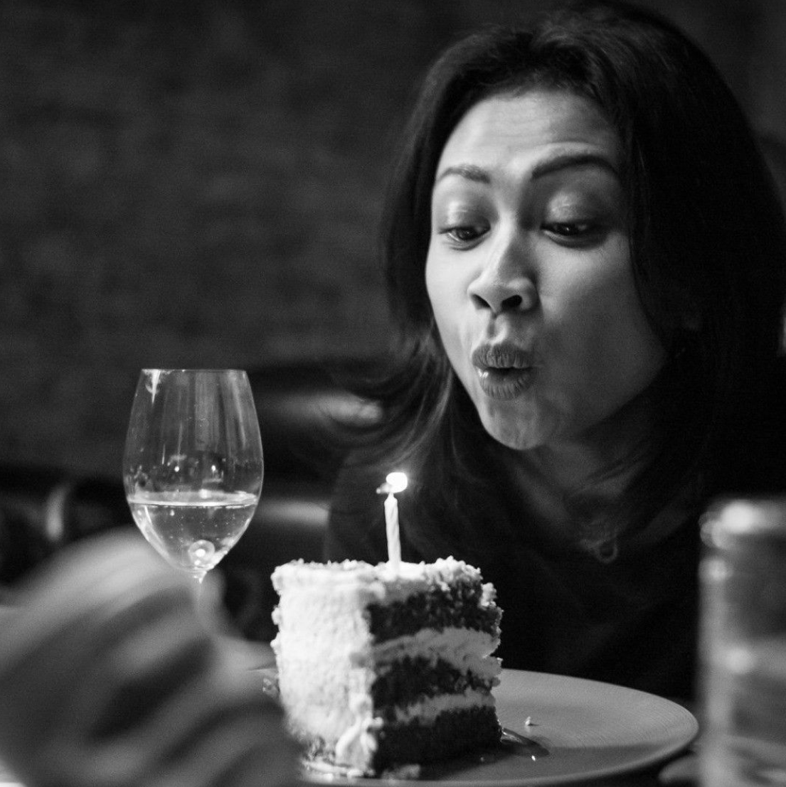 A woman blowing out a candle on a piece of cake in a restaurant.