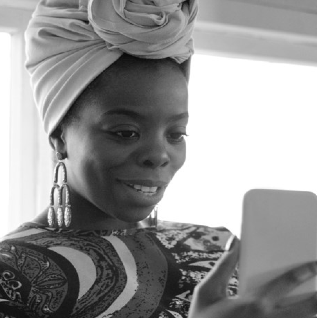 A woman looking at her mobile phone with a smile on her face.